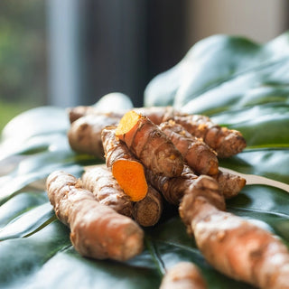 A pile of whole turmeric on a green leaf